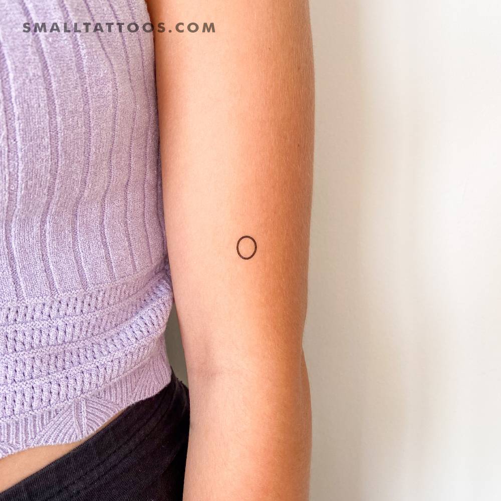 Little minimalistic circle temporary tattoo located on the upper arm.