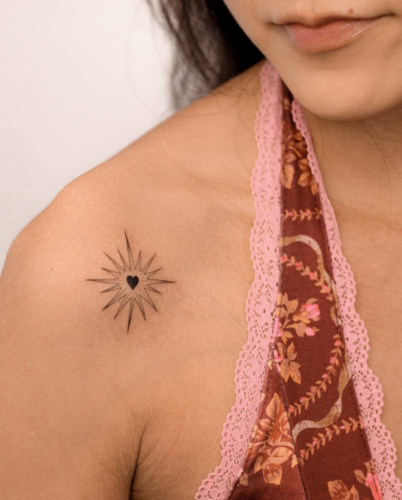 Shining heart tattoo located on the shoulder, illustrative style.
