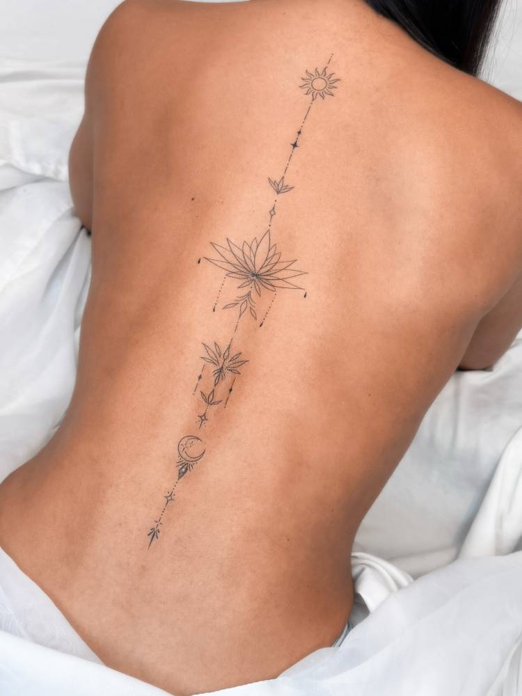Ornamental lotus with sun and moon tattoo located on the spine.