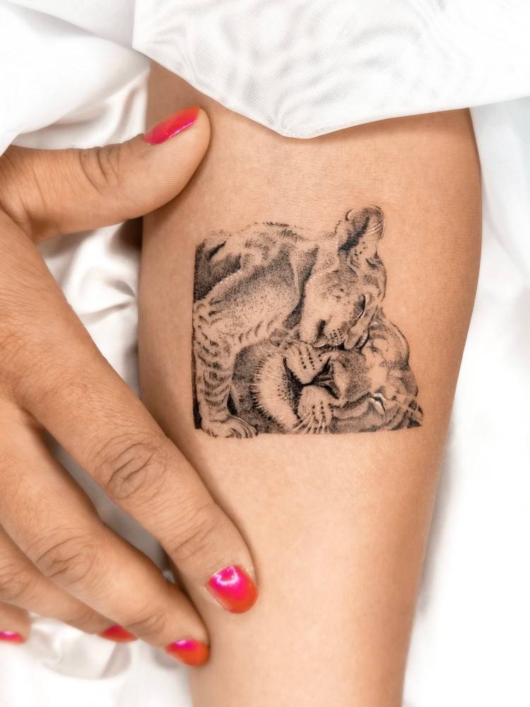 Micro-realistic style lioness and cub tattoo located on the inner forearm.