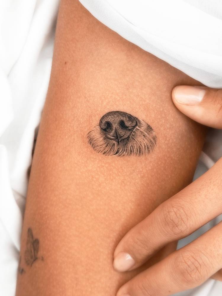 Dog snout tattoo in micro-realistic style located on the upper arm.