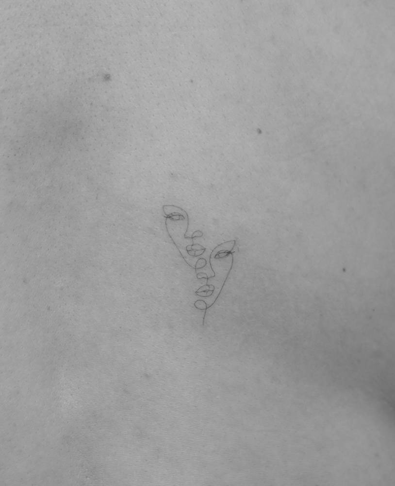 Little faces tattoo in fine line style located on the back.