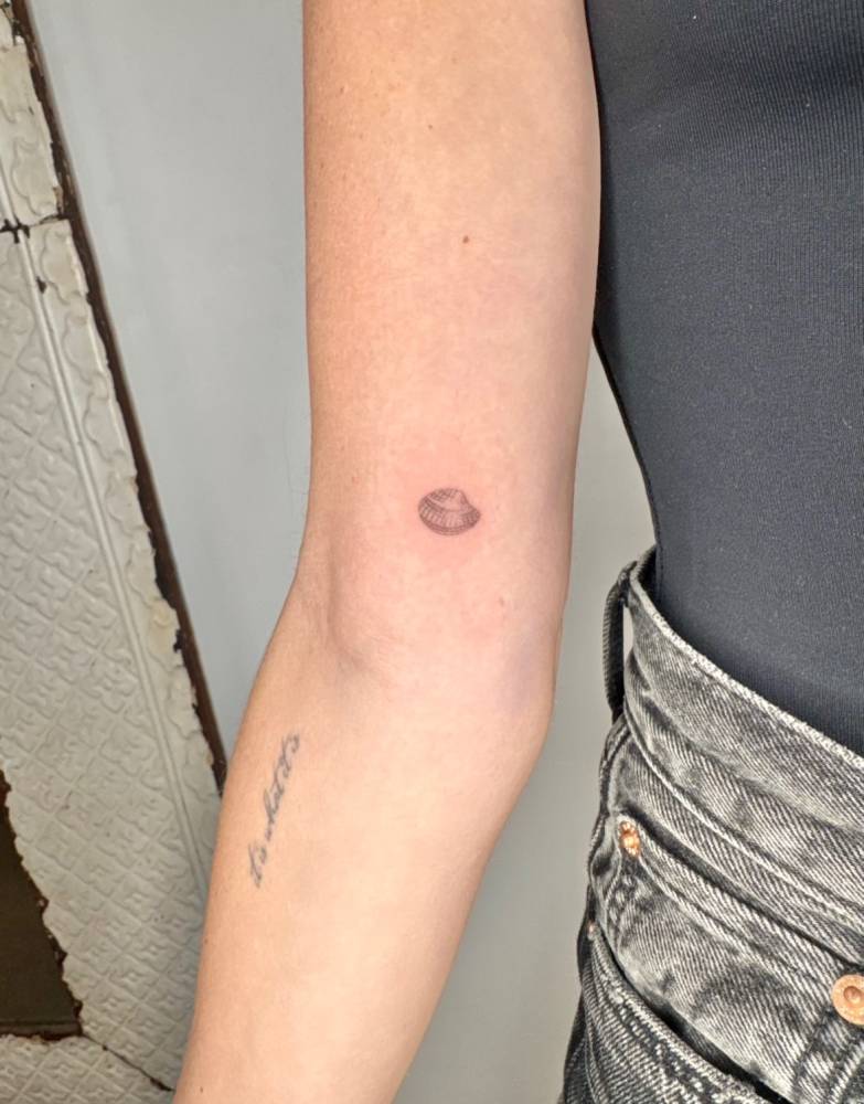 Scallop shell tattoo in micro-realistic style located on the inner arm.