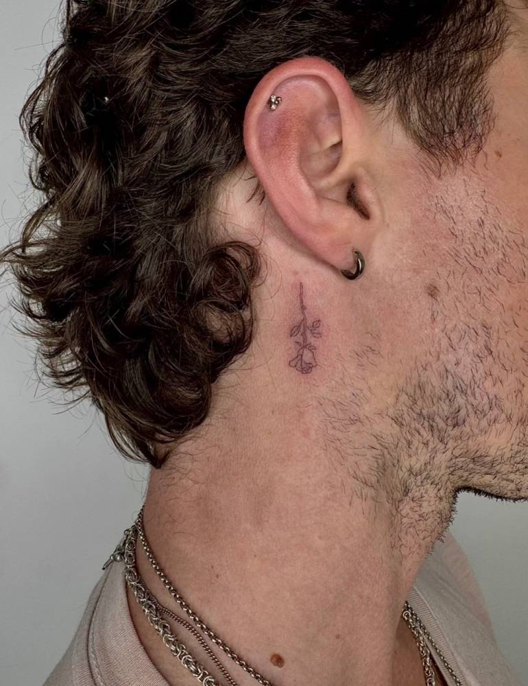 Single needle rose tattoo placed behind the ear.
