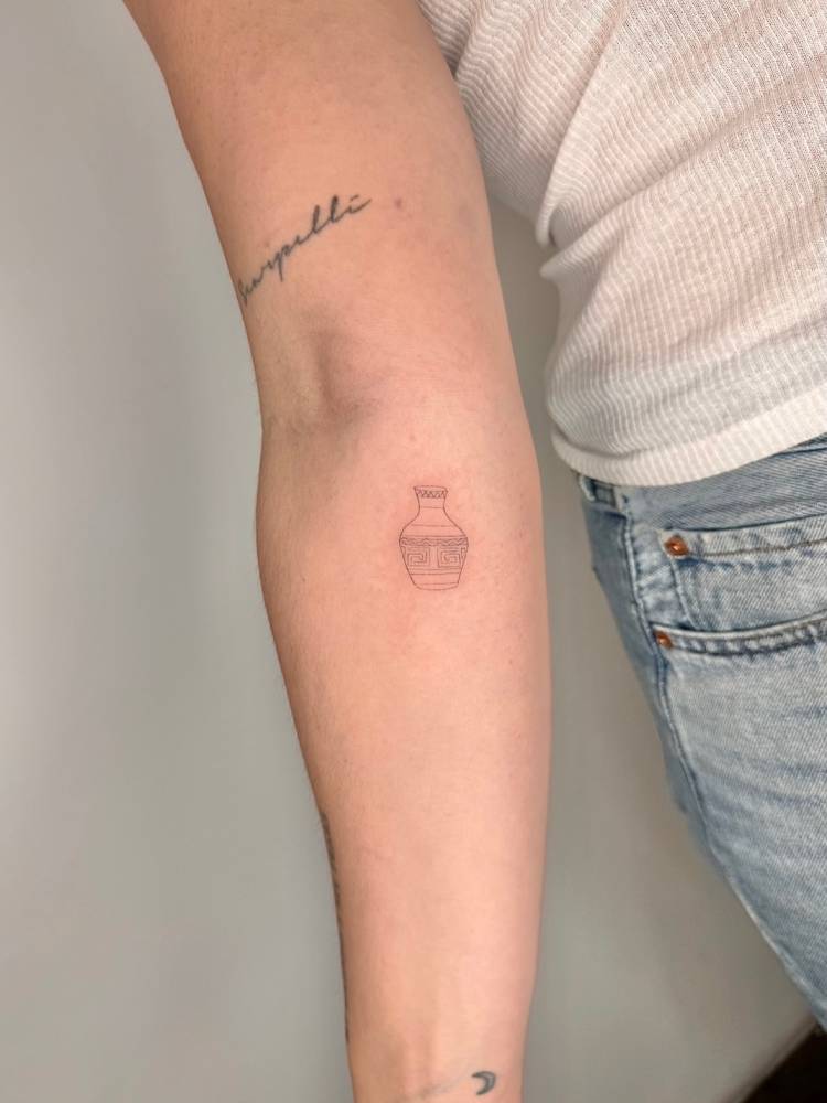 Little vase in fine line style tattooed on the inner forearm.