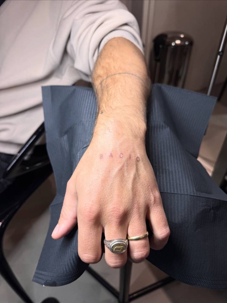 Lettering tattoo of the word "bacio" located on the hand.