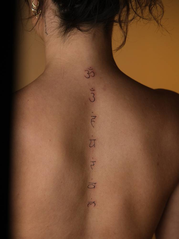 Sanskrit lettering tattooed on the spine.