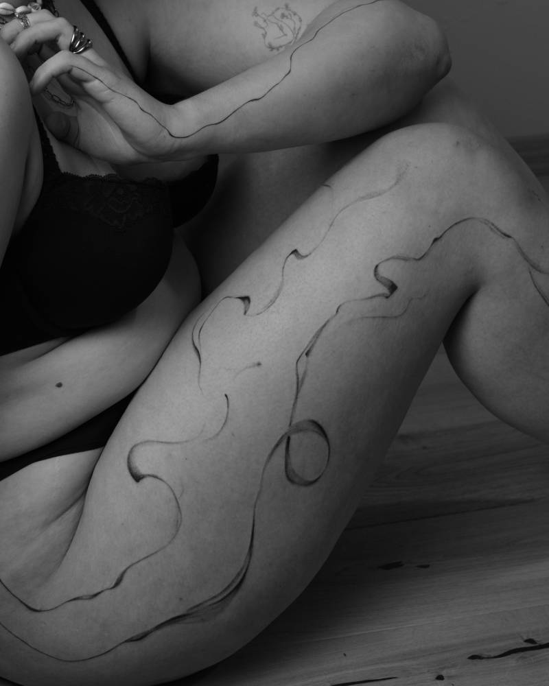Abstract flowely lines tattooed on the thigh.