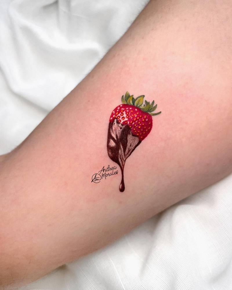 Micro-realistic style chocolate covered strawberry tattoo located on the inner arm.