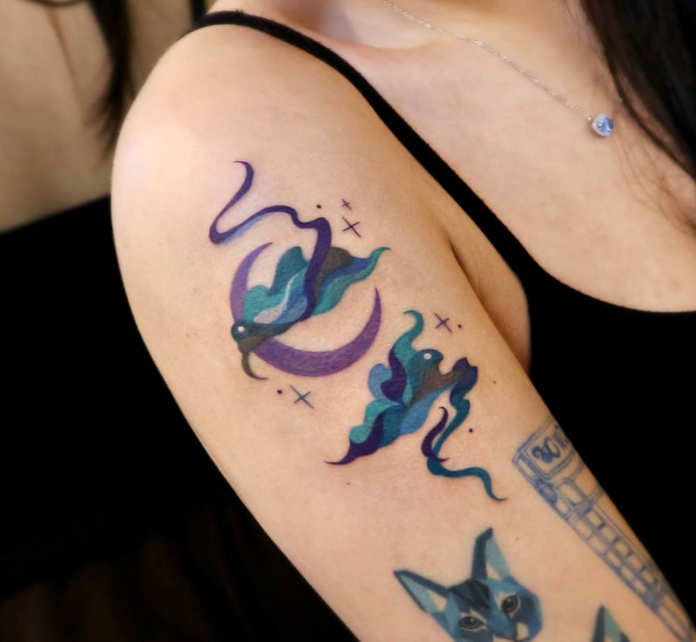 Abstract style clouds and crescent moon tattoo located on the upper arm.