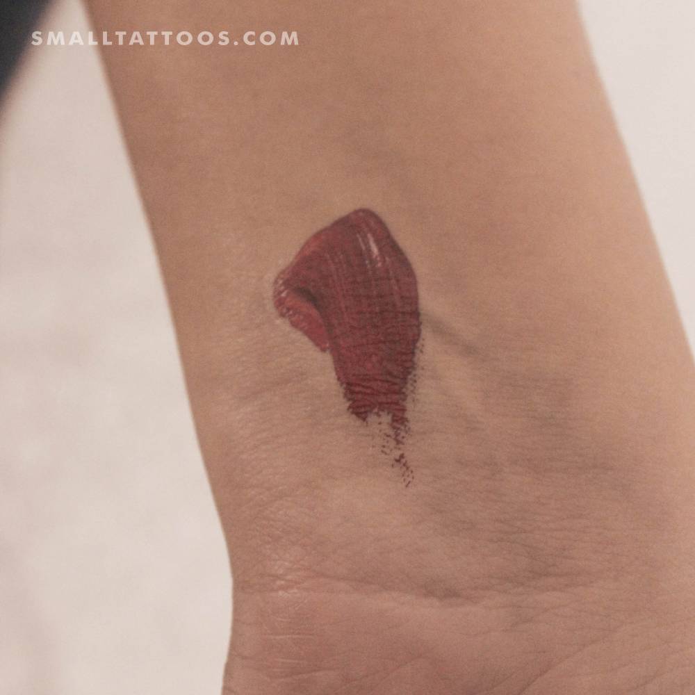 Red brush stroke temporary tattoo located on the wrist.