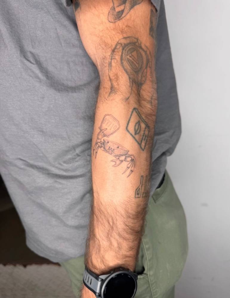 Crab tattoo in illustrative style located on the forearm.