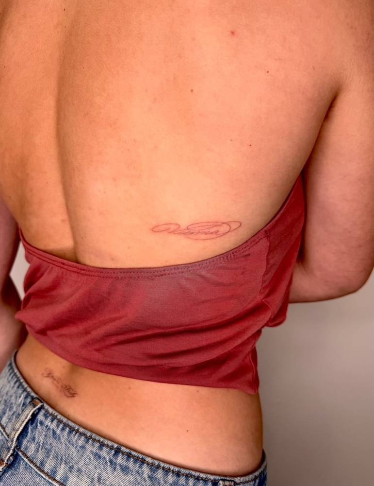 "Vienna" lettering tattoo located located on the back.