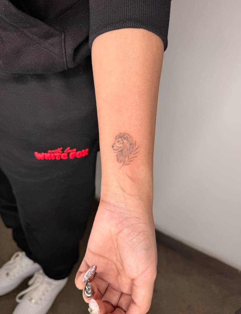 Lion portrait in fine line style tattooed on the wrist.