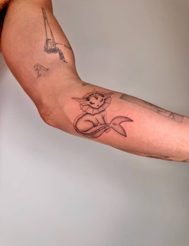 Cartoon style Vaporeon tattoo placed on the inner forearm.