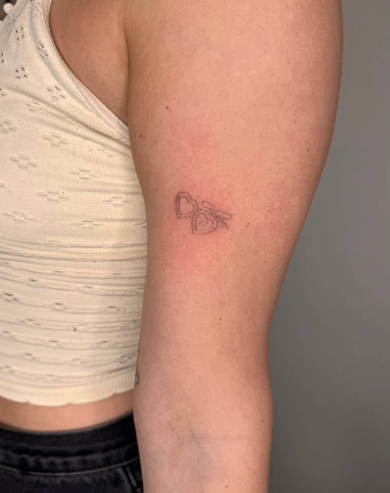 Heart pendant with the number "17" tattooed on the bicep.