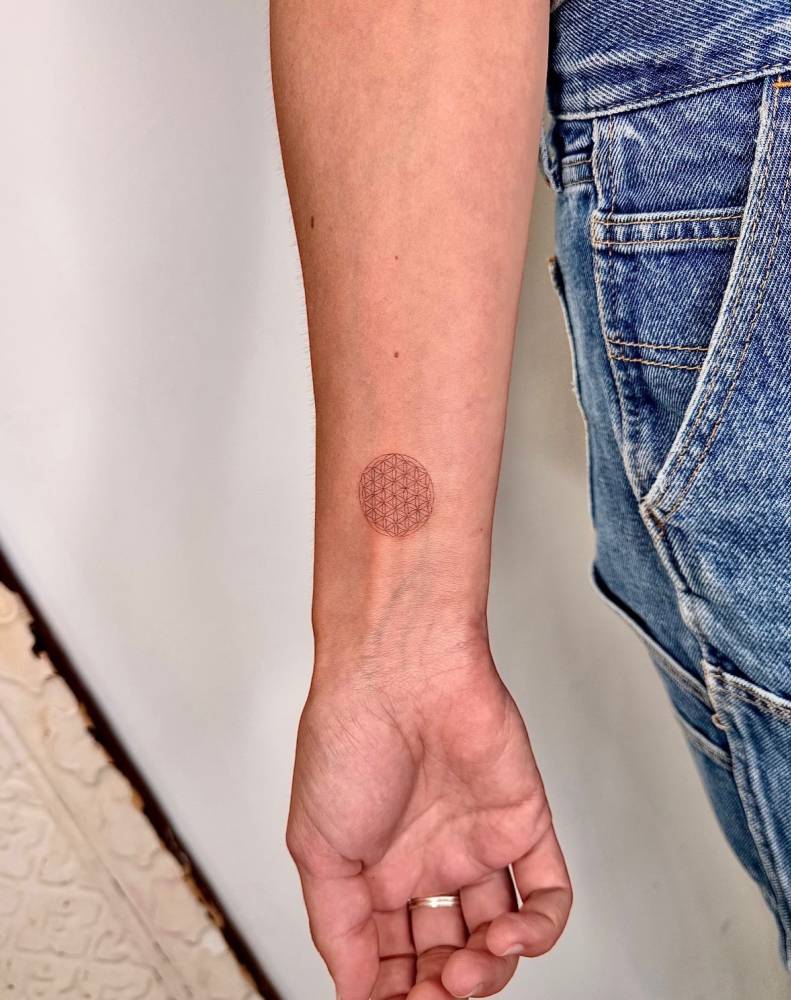 Flower of life tattoo placed on the wrist, fine line style.