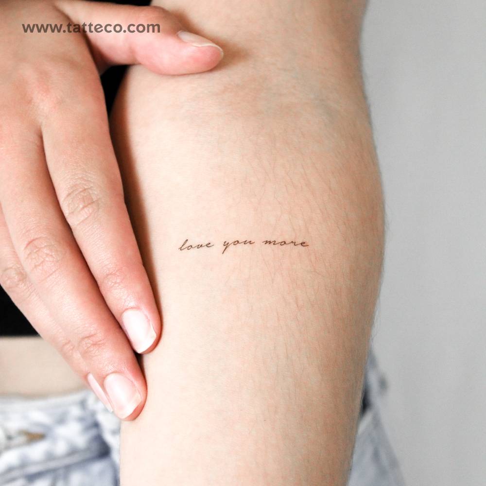 Handwritten font "love you more" temporary tattoo located on the inner forearm.