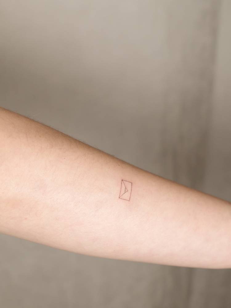 Tiny love letter tattoo located on the forearm, fine line style.
