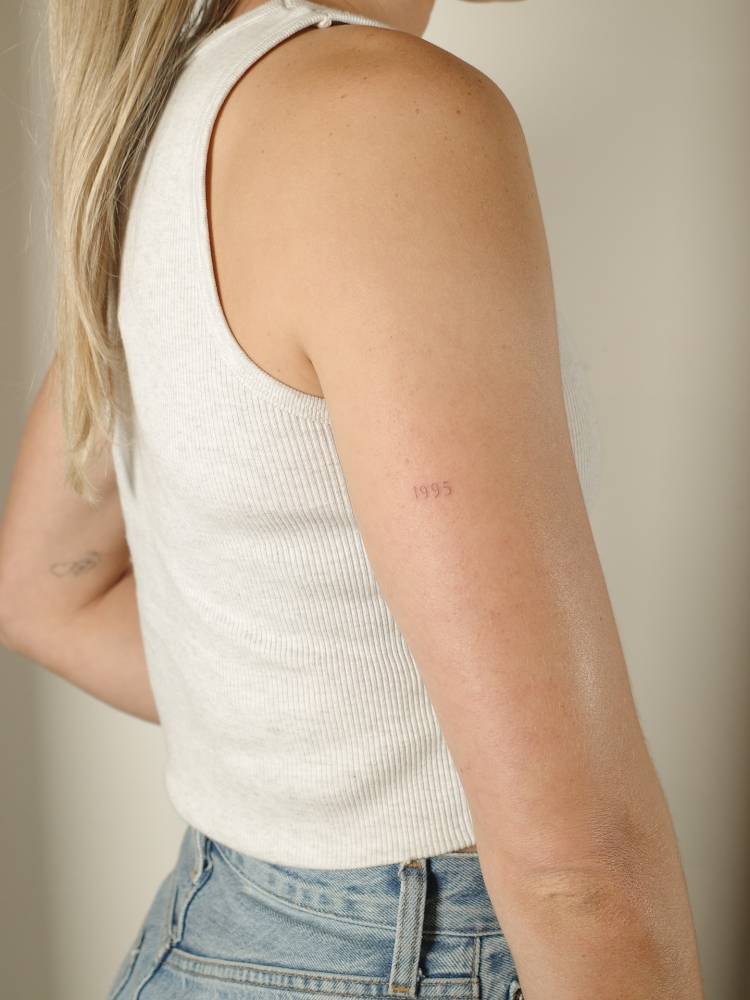 Birth year "1995" lettering tattoo located on the tricep.