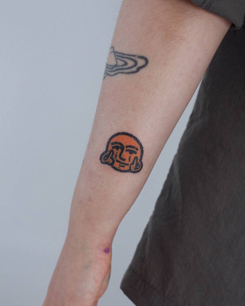Face giving the finger tattooed on the wrist, pop art style.