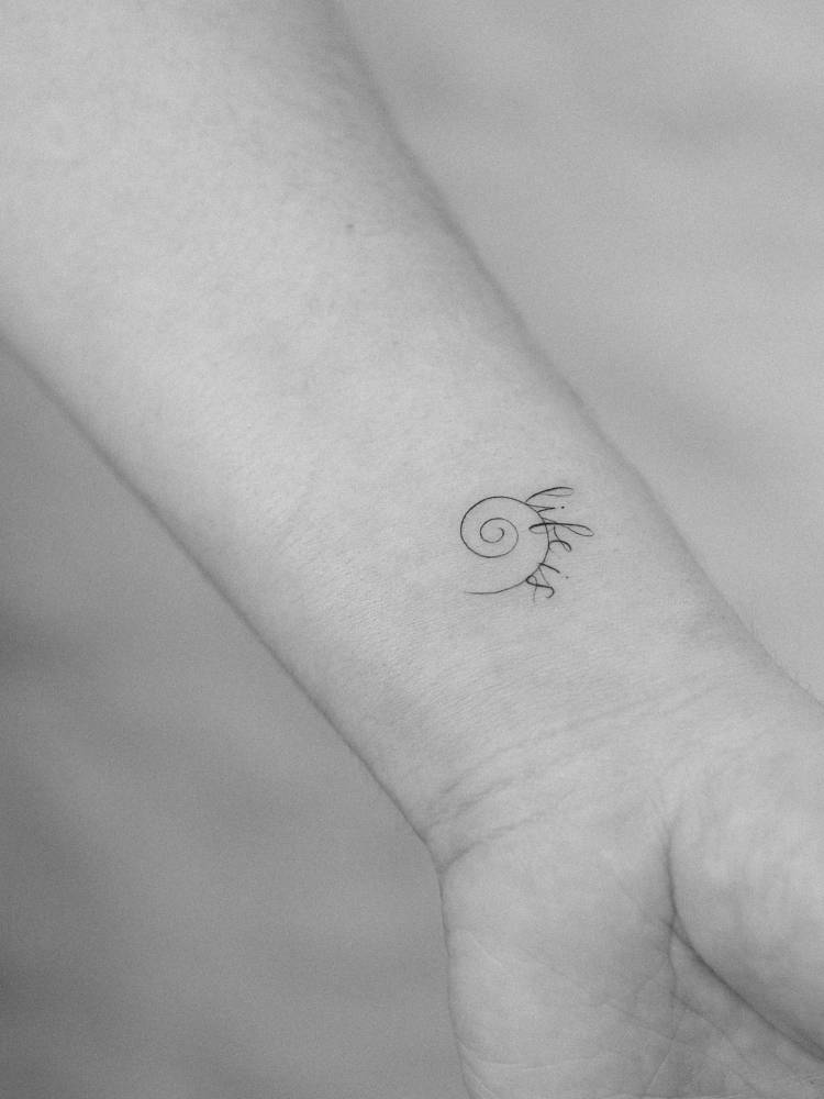 "Life is" and spiral tattoo located on the wrist.