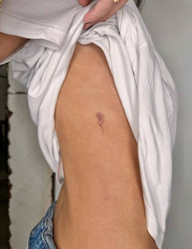 Little fine line rose tattoo located on the side boob.