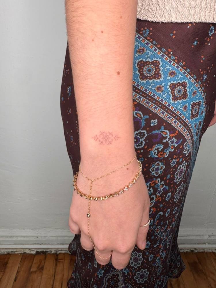 Fine line style small ornament tattoo located on the wrist.