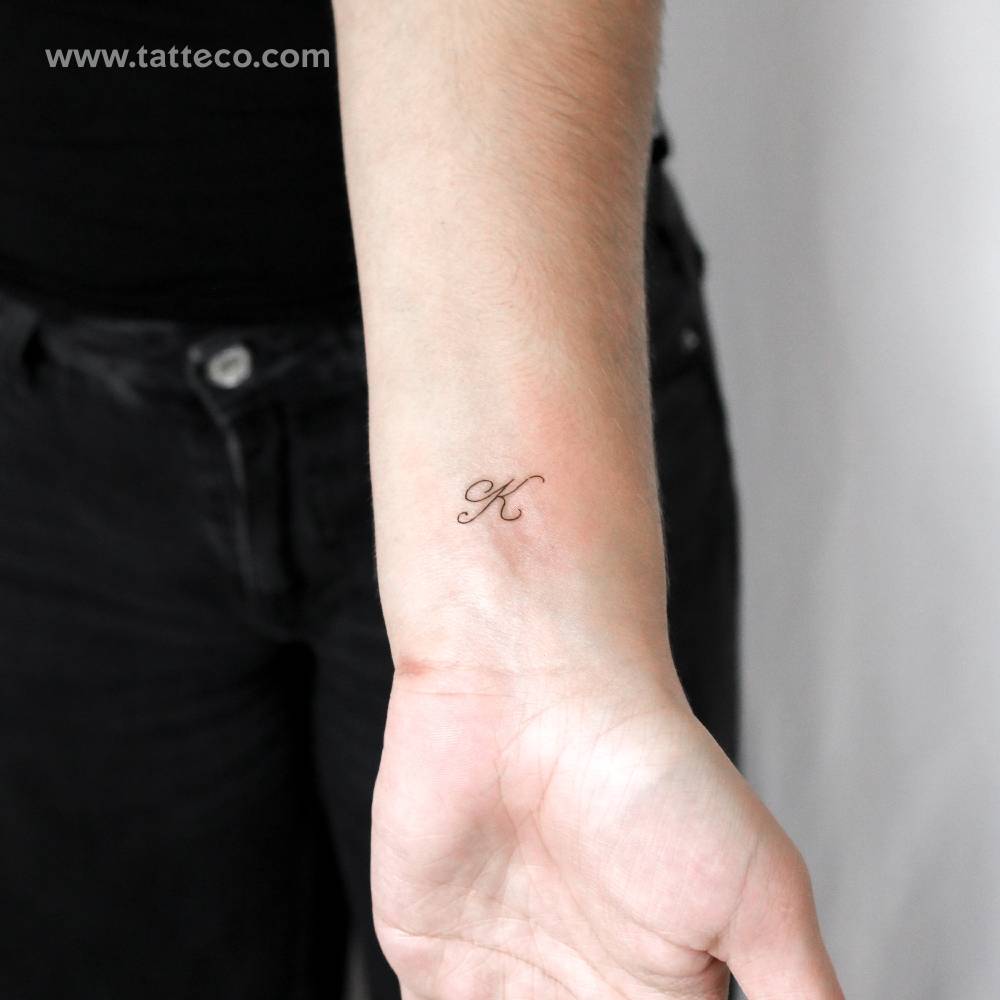 Script font letter "K" temporary tattoo placed on the wrist.