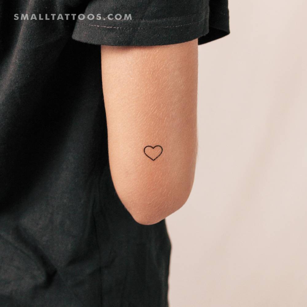 Small minimalist heart outline temporary tattoo placed on the tricep.