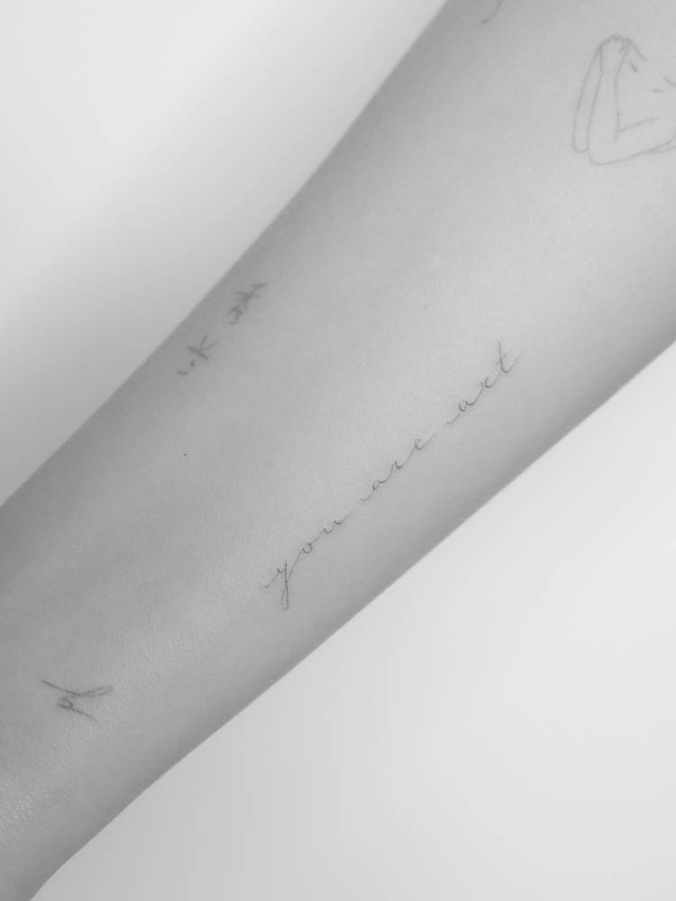 "You are art" lettering tattoo in handwritten font.