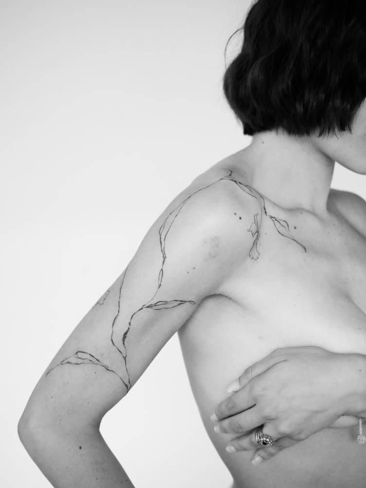 Illustrative style leaves tattoo placed on the upper arm and shoulder.