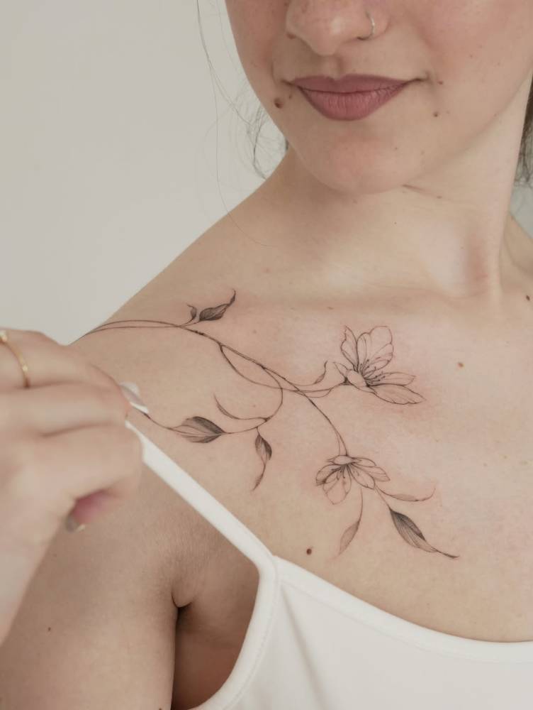 Illustrative style magnolias tattoo located on the shoulder.