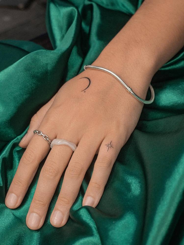 North star and crescent moon tattoo located on the hand.