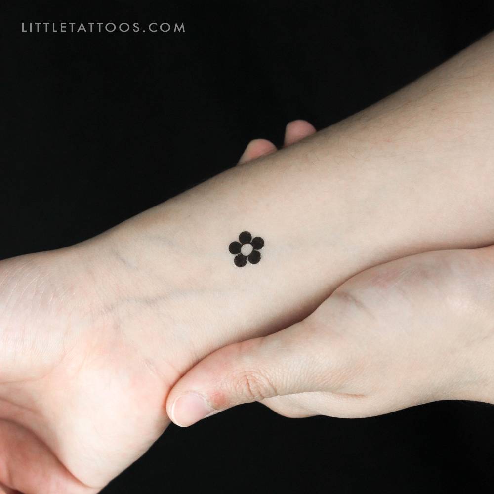 Minimalist style flower temporary tattoo located on the wrist.