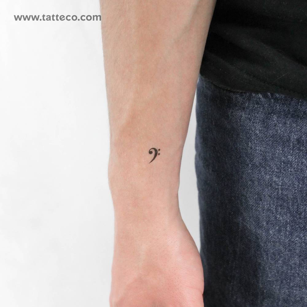 Tiny bass clef temporary tattoo placed on the wrist.
