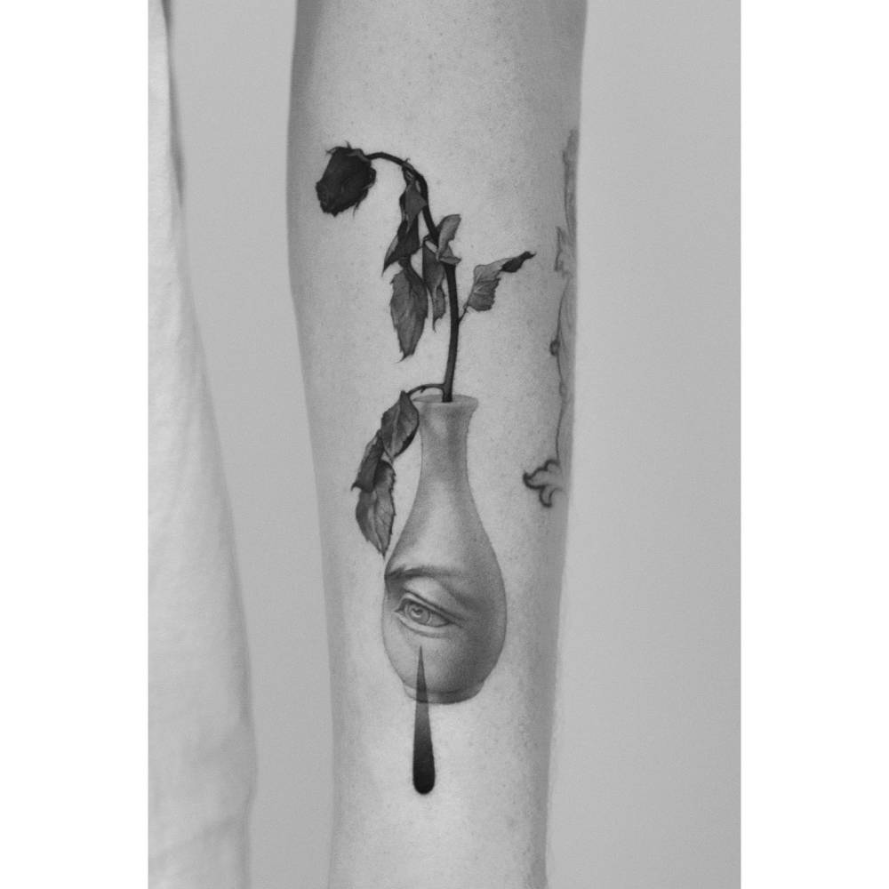 Flower in a bottle tattoo located on the forearm, micro-realistic style.