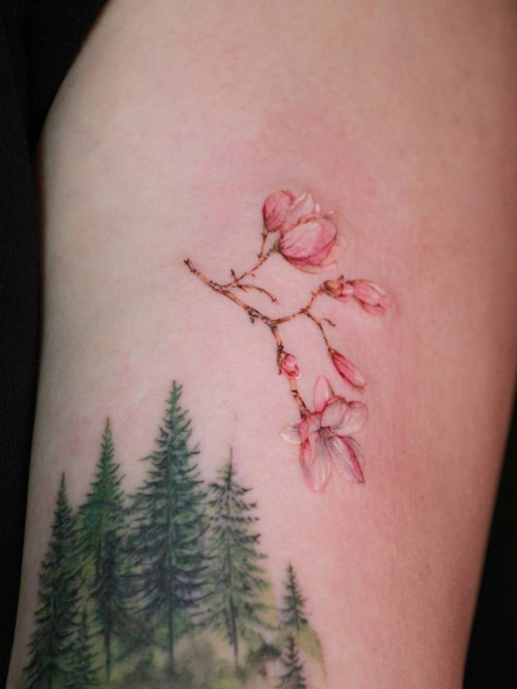 Watercolor style cherry blossom tattoo located on the upper arm.