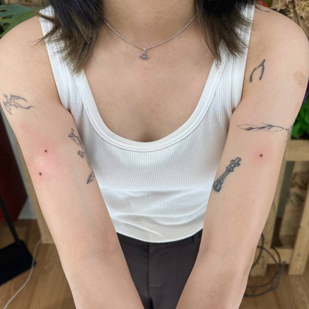 Tiny minimalistic stars tattooed on the upper arms.