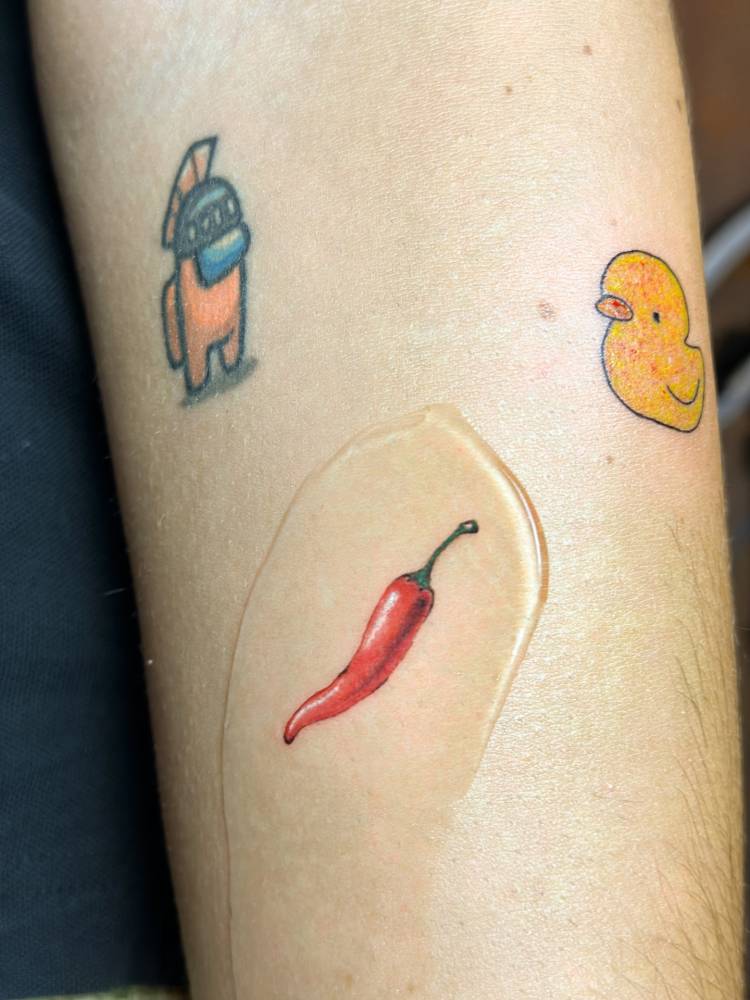 Red chili pepper tattoo in illustrative style located on the forearm.