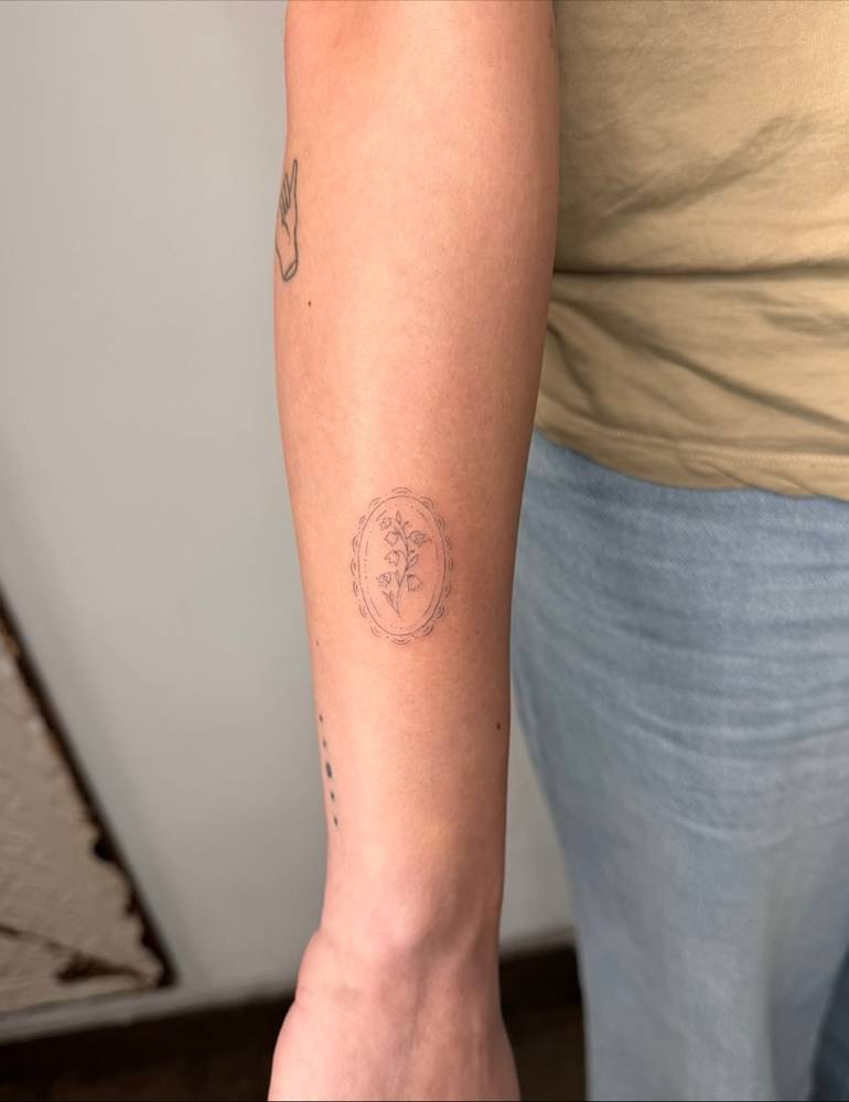 Lily of the valley tattoo in fine line style done on the forearm.