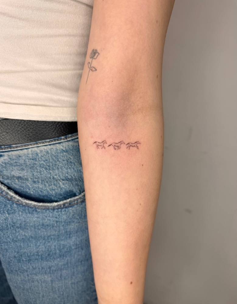 Horses tattoo in illustrative style located on the inner forearm.
