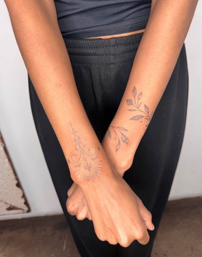 Ornament and leaves bracelet tattoos located on the wrists.