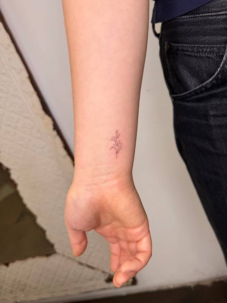 Little flowers tattoo in fine line style placed on the wrist.