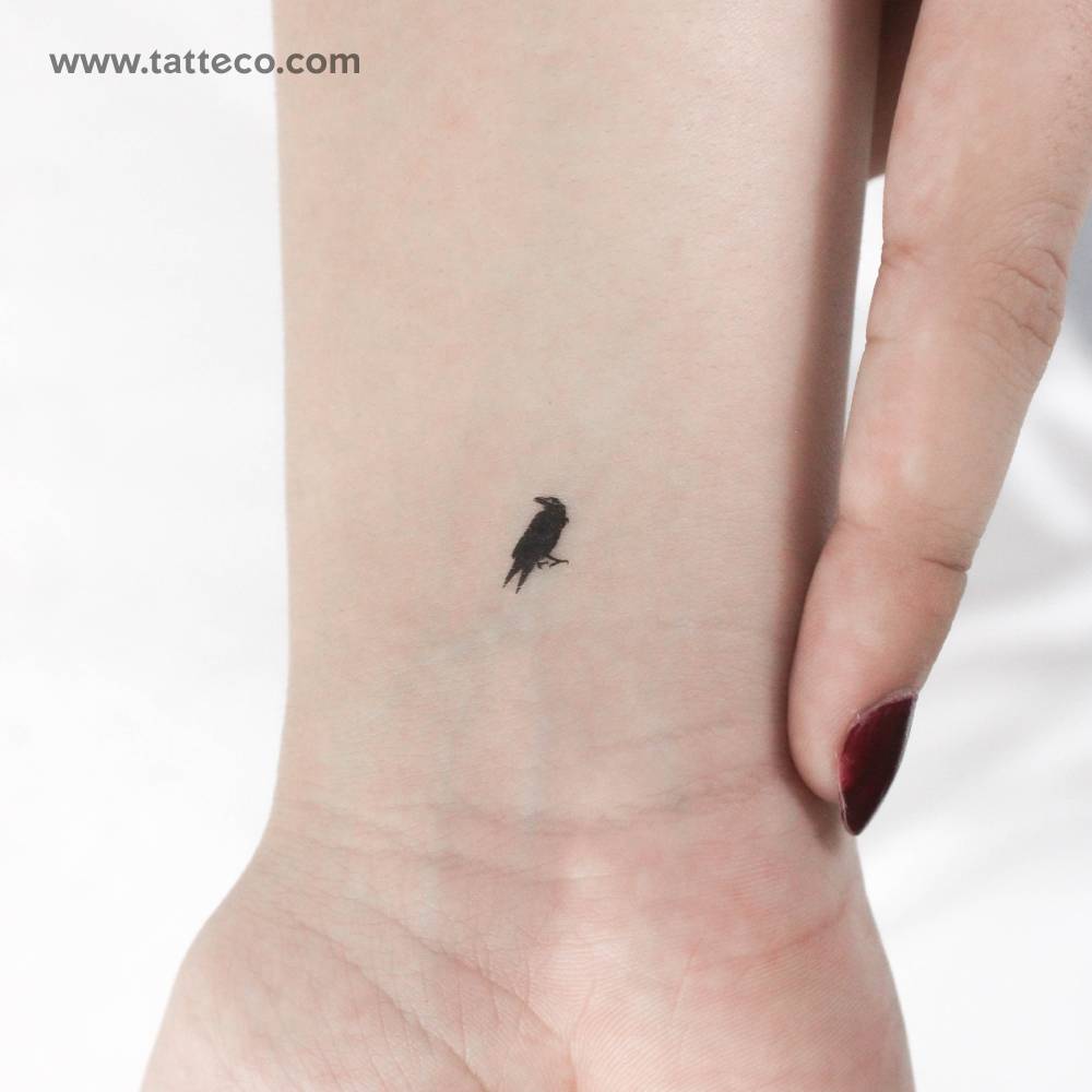 Tiny crow temporary tattoo located on the wrist.