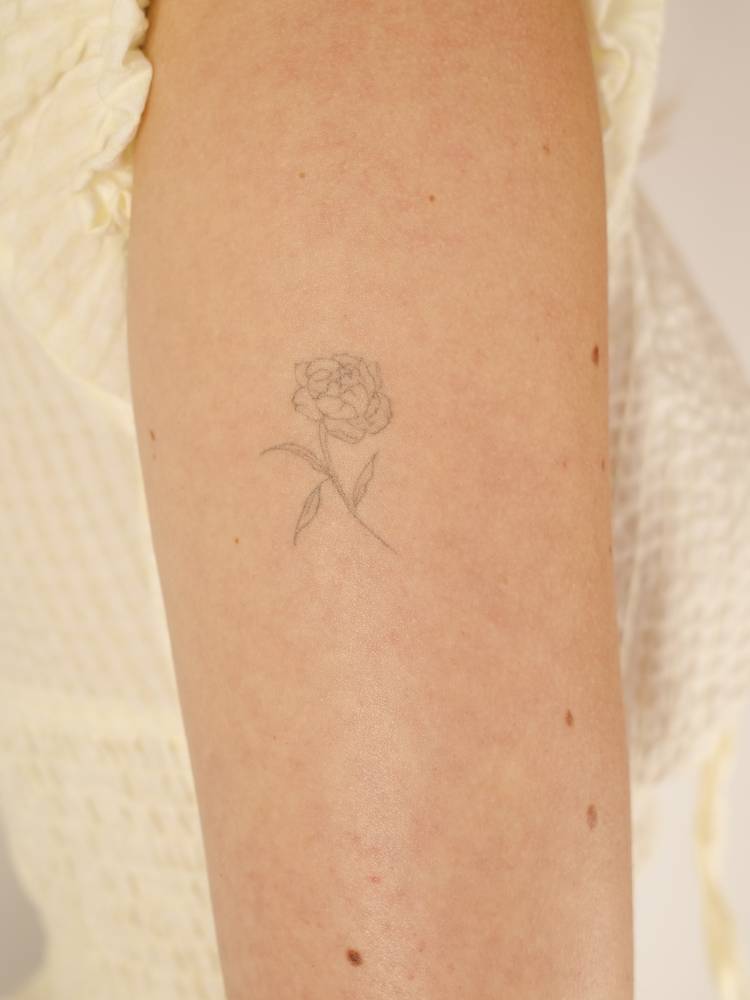 Peony tattoo in fine line style placed on the inner forearm.