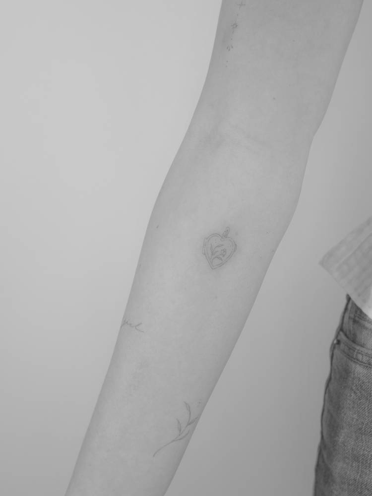 Little heart pendant tattoo done on the inner forearm, fine line style.
