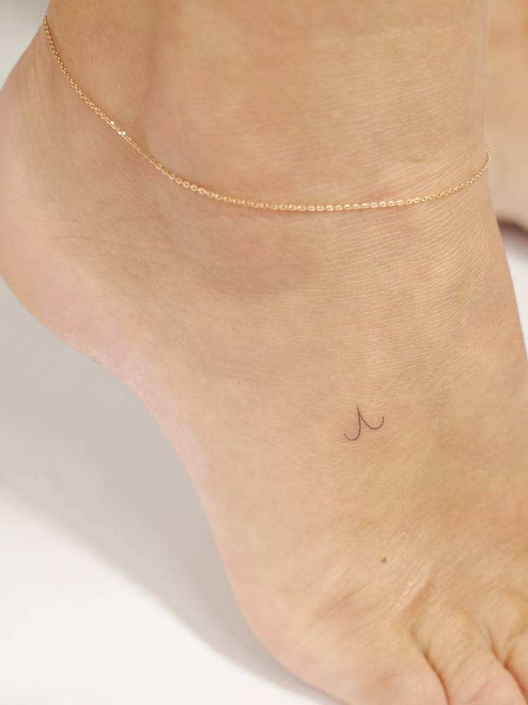 Micro Aries Zodiac symbol tattoo located on the foot.