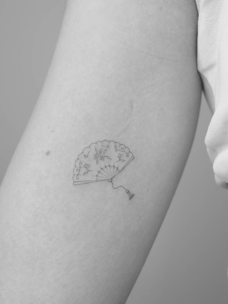 Fine line style hand fan tattoo done on the inner arm.