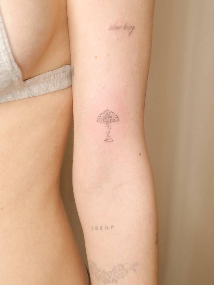 Lamp tattoo in fine line style located on the bicep.